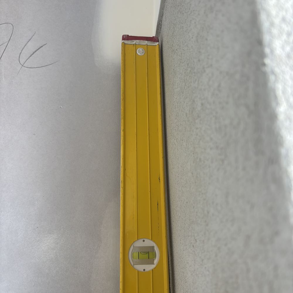 Wall leaning more than 5mm out of plumb across its height, found during a fixing inspection in Sunbury