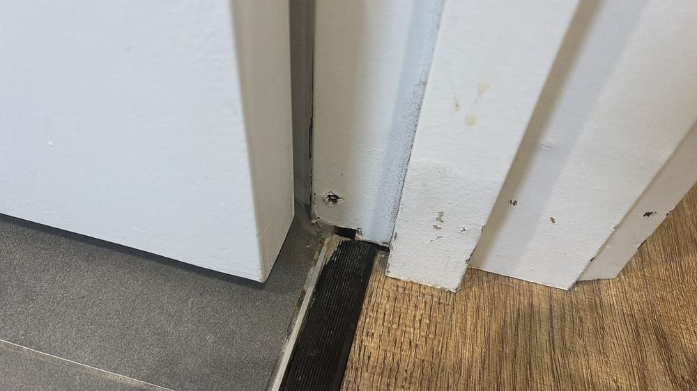 Moisture damage spreading into the floor finish near the shower, found during a defect investigation in Epping
