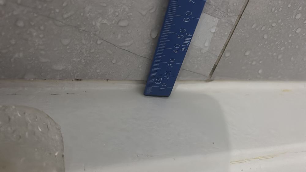 Wall tiles stopping short of the shower tray upturn, leaving the joint exposed, found during a defect investigation in Epping